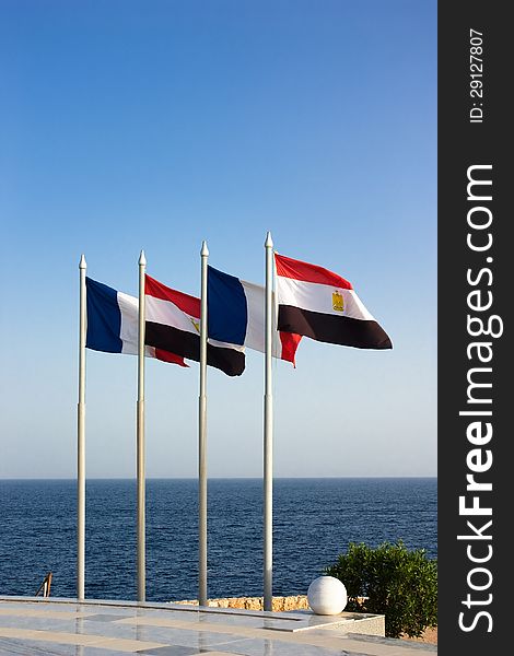 French and Egyptian flags flies in the wind on the blue sea on the background of the clear sky under sunlight. French and Egyptian flags flies in the wind on the blue sea on the background of the clear sky under sunlight