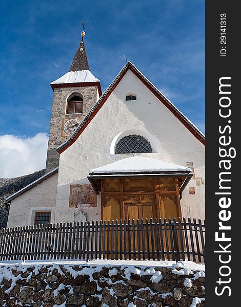 A wintertime view of a small church with a tall steeple in Montassilone, Sud Tyrol