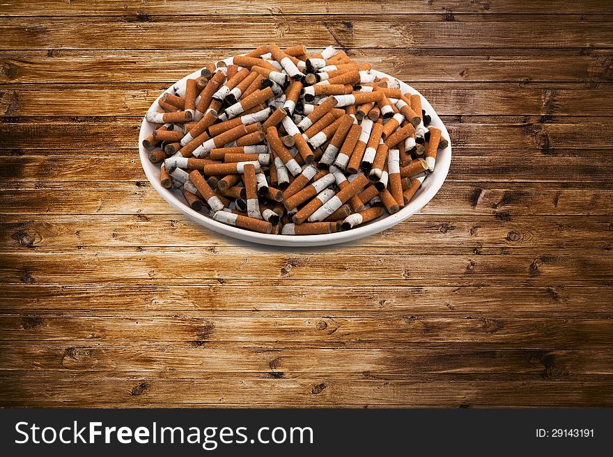 White ceramic plate with cigarettes on wooden surface
