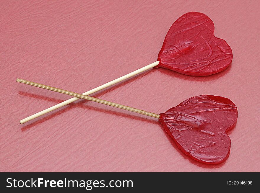 Two heart shape lollipops with a red background