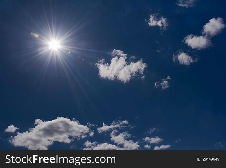 Radiant sun on blue sky with some clouds
