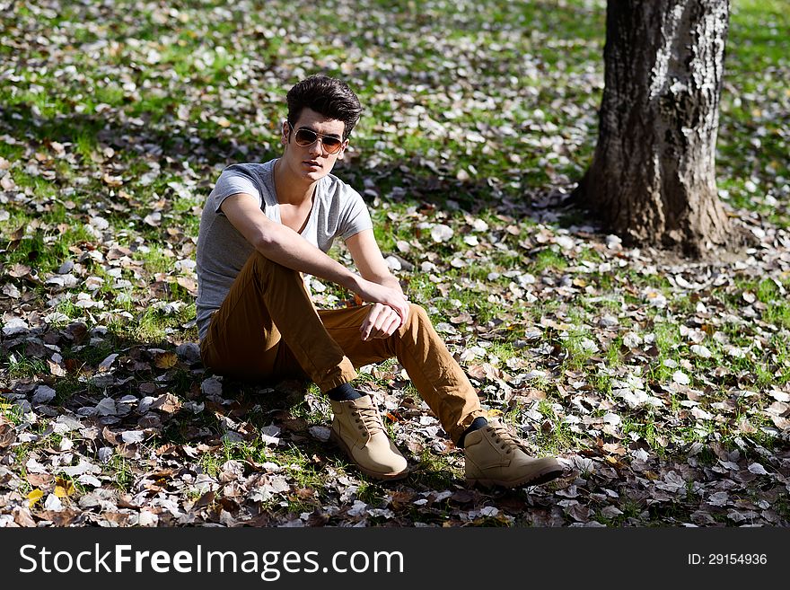 Portrait of a young handsome man, model of fashion, with modern hairstyle in the park. Portrait of a young handsome man, model of fashion, with modern hairstyle in the park