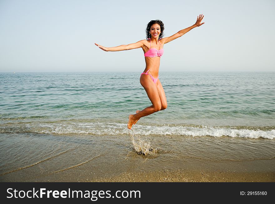 Woman with beautiful body jumping in a tropical beach