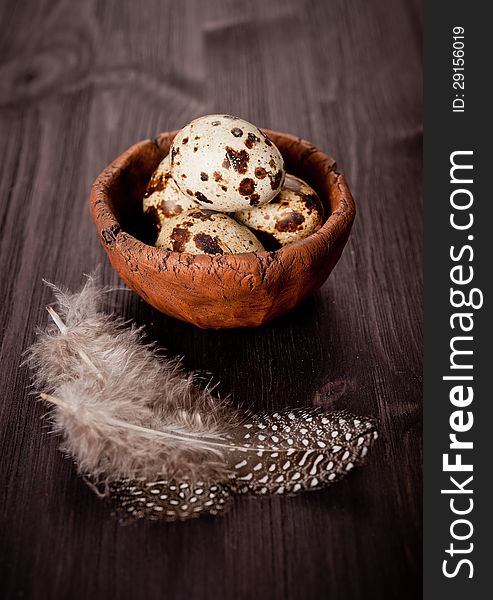 Quail eggs with feathers on a wooden board