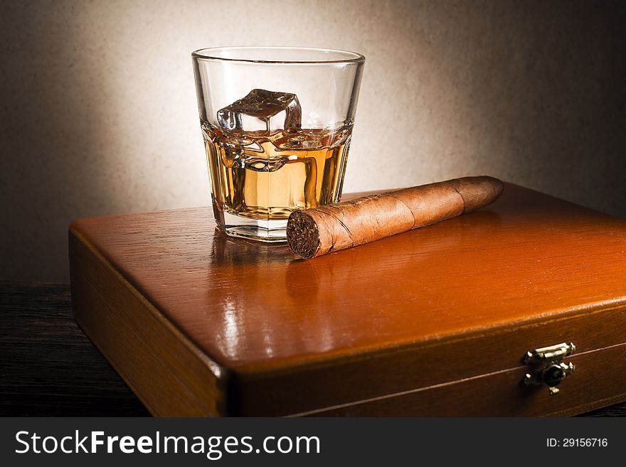 Whiskey and cigar on wooden box close up