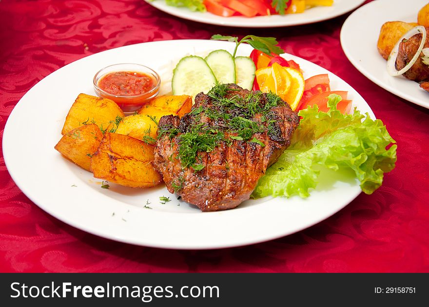 Grilled beefsteak, baked potatoes and vegetables