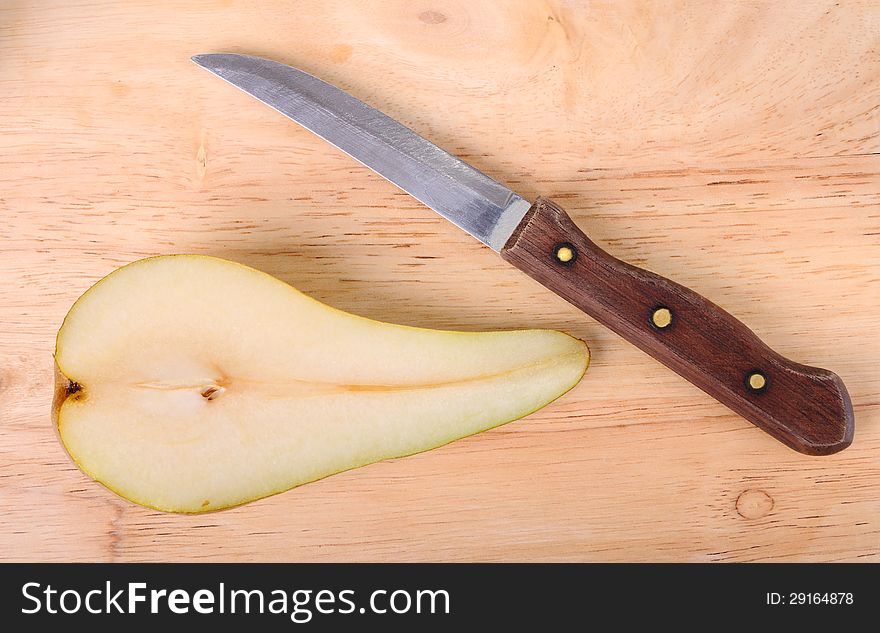 Half of a pear and knife is on a chopping board