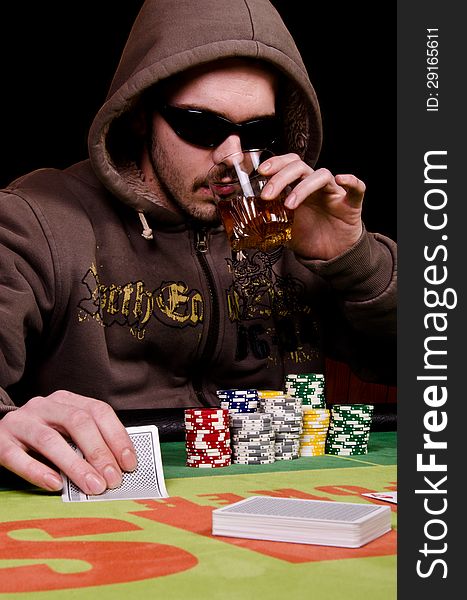 Poker player is drinking and looking his cards. Poker player is drinking and looking his cards.