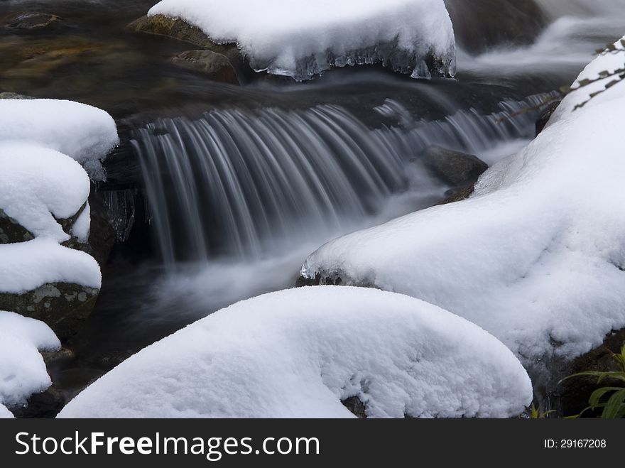 Small waterfall on a stream covered in snow
