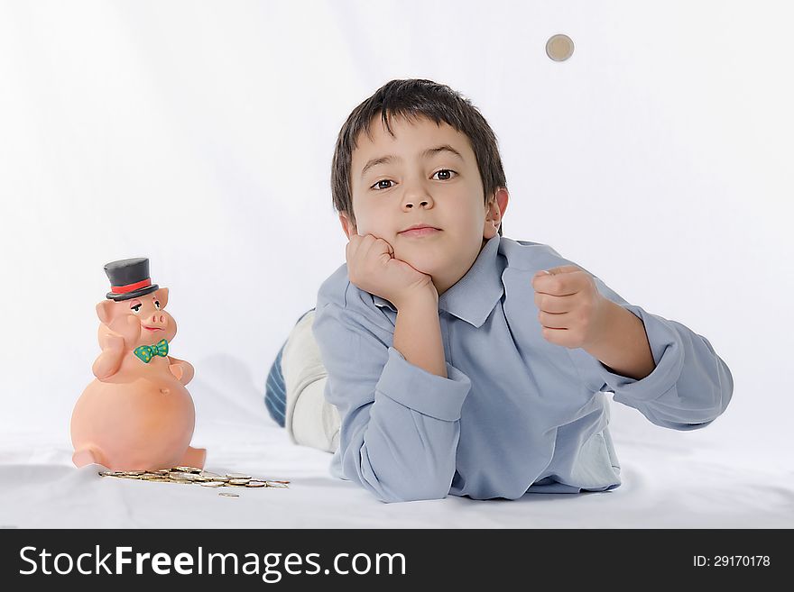 Piggy bank and child on a white background brightly lit. the child throws a coin in the air.