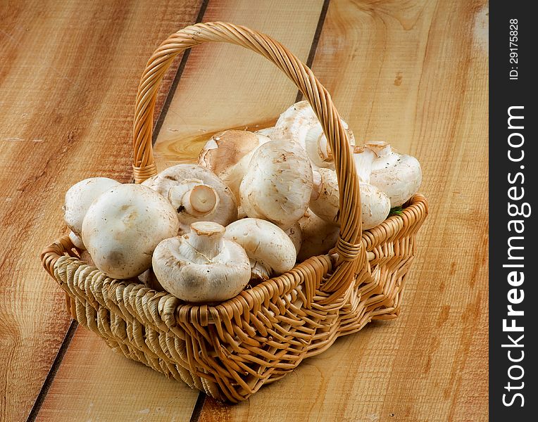 Basket with Perfect Big Raw Champignons closeup on Wooden background. Basket with Perfect Big Raw Champignons closeup on Wooden background