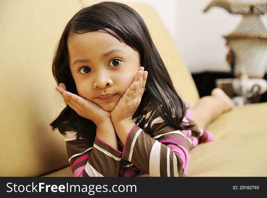 Beautiful young girl look emptily looking at the camera on the couch. Beautiful young girl look emptily looking at the camera on the couch