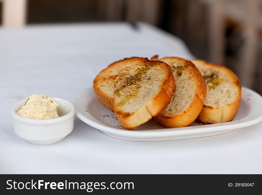 Toasted bread with garlic and spices on a white plate and butter. Toasted bread with garlic and spices on a white plate and butter