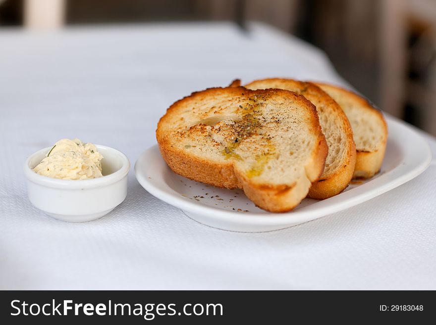 Toasted bread with garlic and spices on a white plate and butter. Toasted bread with garlic and spices on a white plate and butter