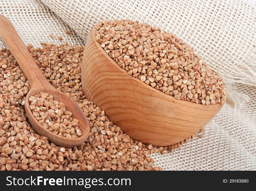 Raw buckwheat in wooden bowl and spoon on burlap, food ingredient photo