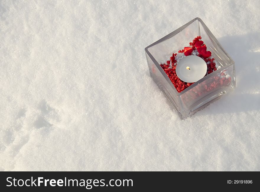 Candle with red decoration in snow