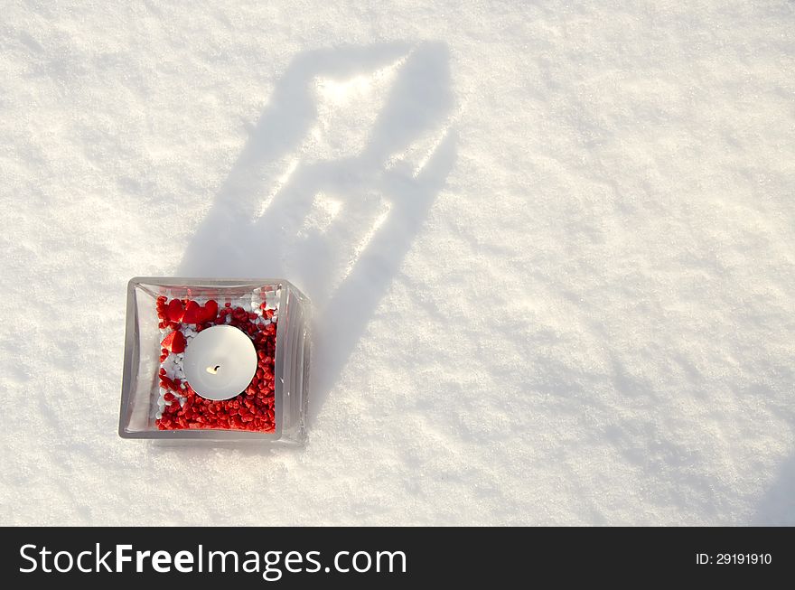 Candle with red decoration on snow