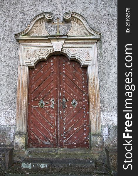 Ornate wooden doors of the church, cross above the door
