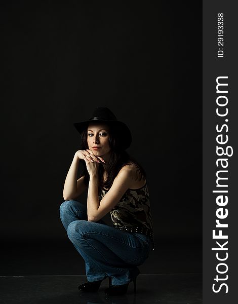 Pretty woman in black hat posing sitting in studio. Pretty woman in black hat posing sitting in studio