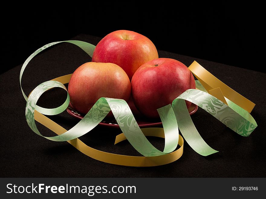 Red apples on a black background with color ribbons. Red apples on a black background with color ribbons