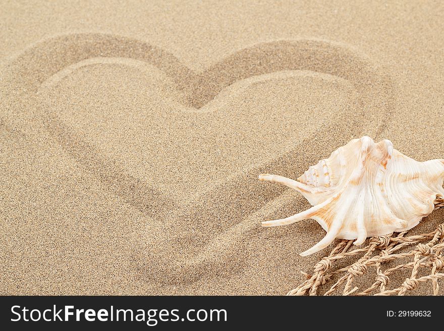 Handwritten heart on yellow soft sand with seashell and shallow focus. Handwritten heart on yellow soft sand with seashell and shallow focus