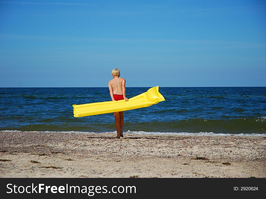 A boy with yellow airbed on the beach
