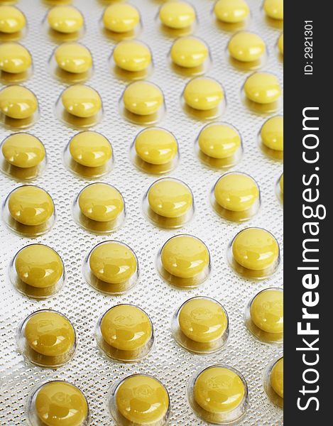 Yellow and round tablets in a factory packing. Yellow and round tablets in a factory packing