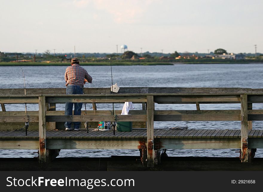 A fisherman alone on a pier. A fisherman alone on a pier