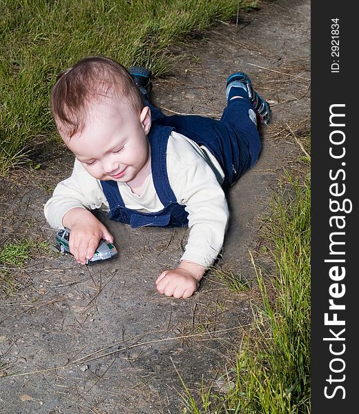 Happy boy laying in the park and playing with toy car. Happy boy laying in the park and playing with toy car