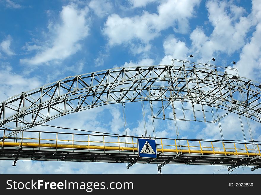 Pedestrian bridge crossing cloudy sky. Pedestrian bridge crossing cloudy sky