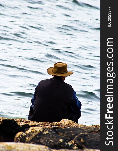 A man sitting thinking by the water's edge. A man sitting thinking by the water's edge.