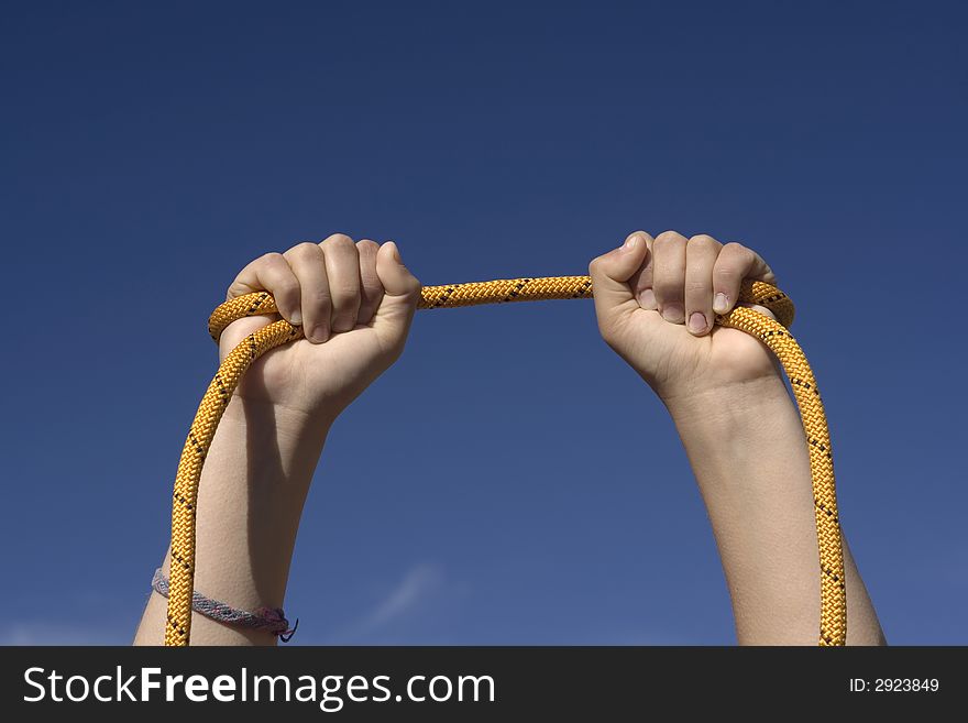 Two hands with an orange rope on sky background