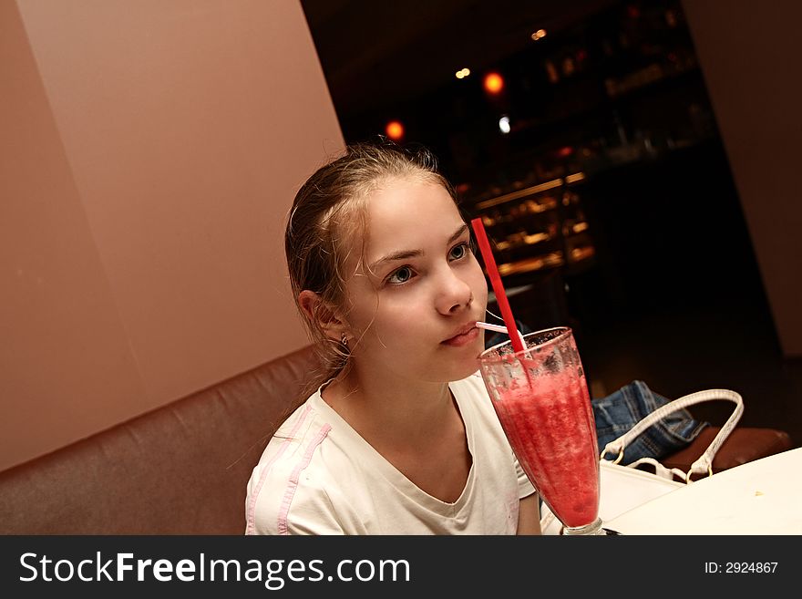 The girl drinks fruit cocktail in cafe. The girl drinks fruit cocktail in cafe