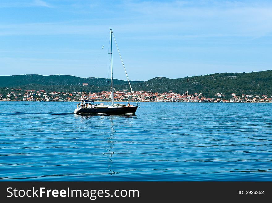 Sailing boat on sea, in background coast with townlet, Croatia