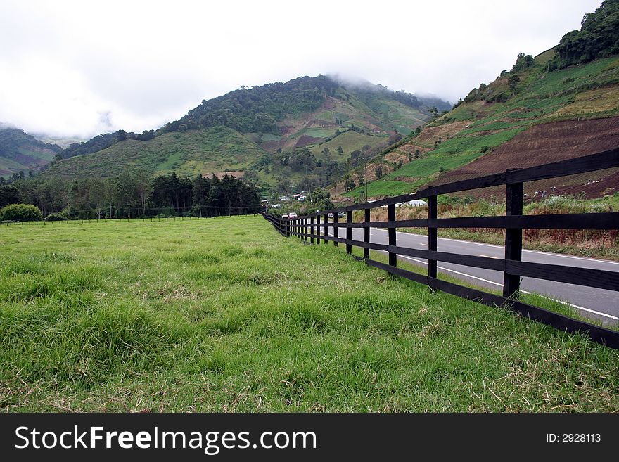 A fence running along a rural road. A fence running along a rural road