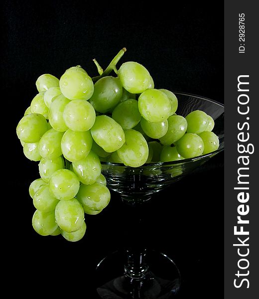 Cluster of green grapes falling out of a glass. Cluster of green grapes falling out of a glass