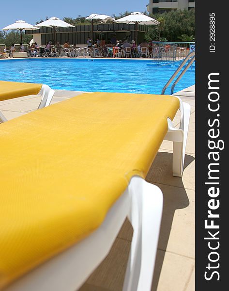 Pool sunbeds closeup with pool water and bar as background