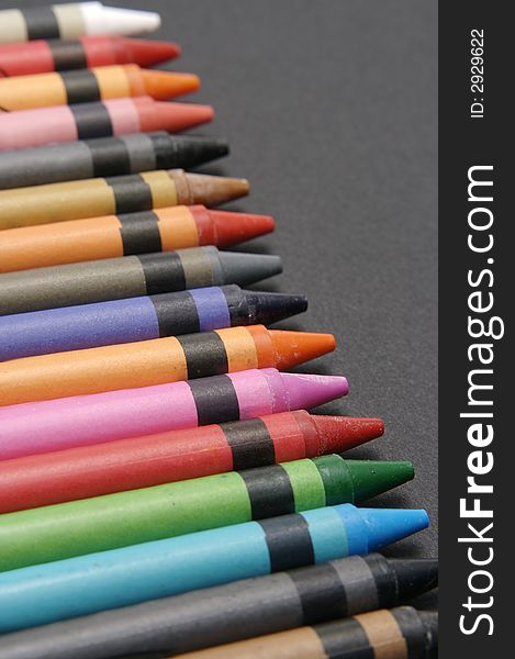 A set of colourful crayons against a black background. A set of colourful crayons against a black background.