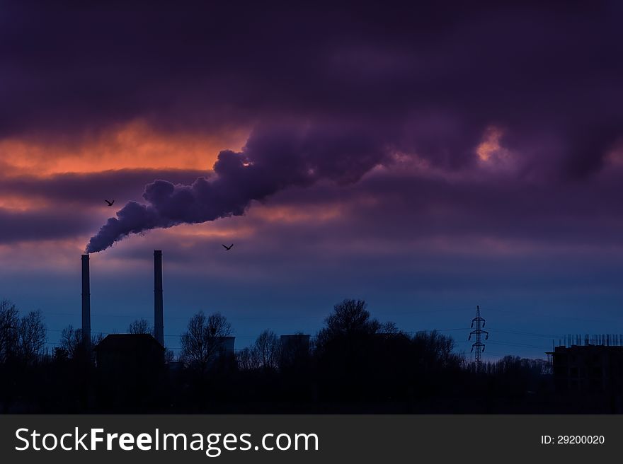 Heavy smoke spewed from the stacks of a coal power plant, profiled on dramatic cloudy sky. Heavy smoke spewed from the stacks of a coal power plant, profiled on dramatic cloudy sky