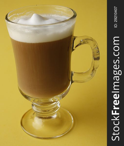 Glass mug of coffee with yellow back round