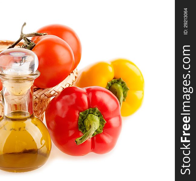 Pepper and a bottle with olive oil on the background of the wattled dish with the vegetables on the white