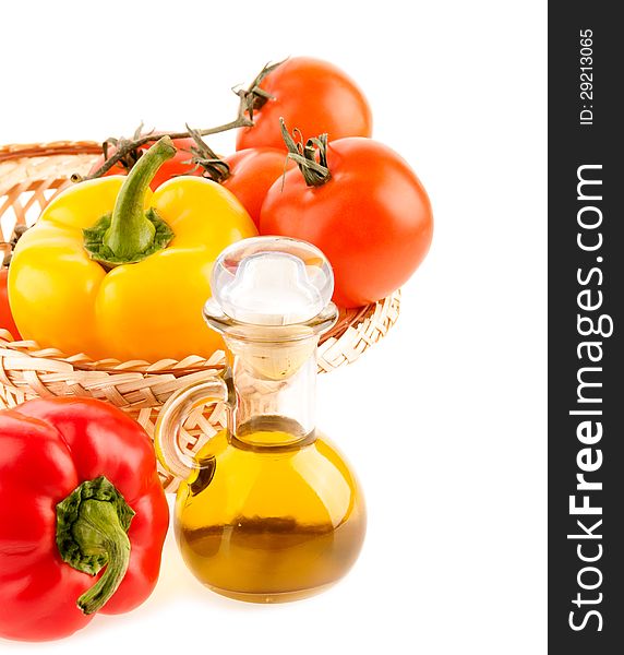 Pepper and a bottle with olive oil on the background of the wattled dish with the vegetables on the white