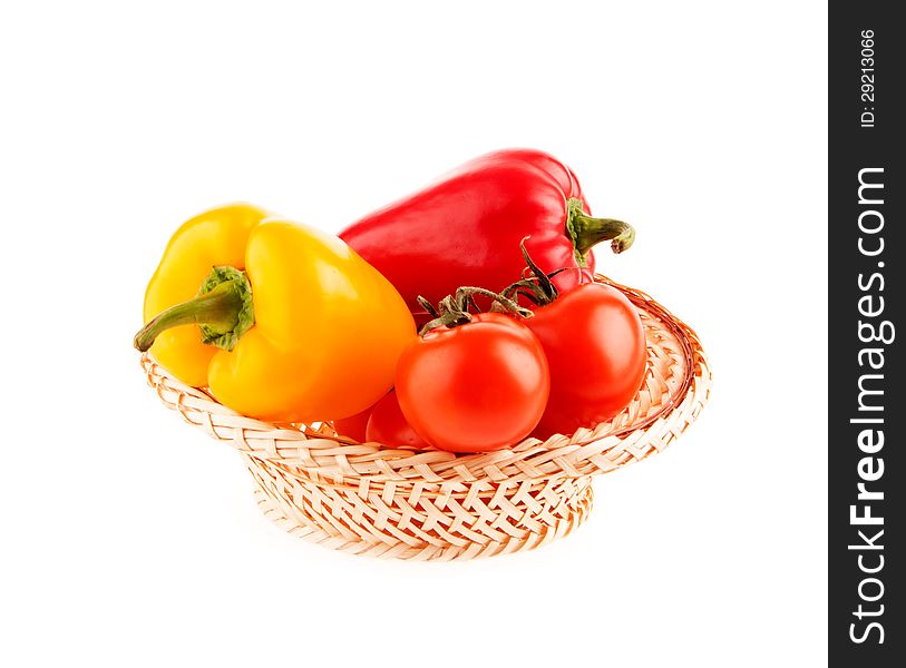 Tomatoes and peppers in a wicker basket on a white background