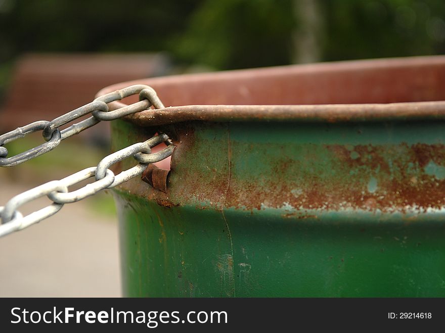 Image of a chained rusted garbage can in a park. Selective focus on where the chain is connected to the garbage can. Lots of space for content. Image of a chained rusted garbage can in a park. Selective focus on where the chain is connected to the garbage can. Lots of space for content.