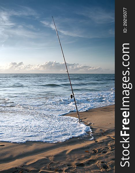 Fishing Pole in Sand with waves on shore. Fishing Pole in Sand with waves on shore