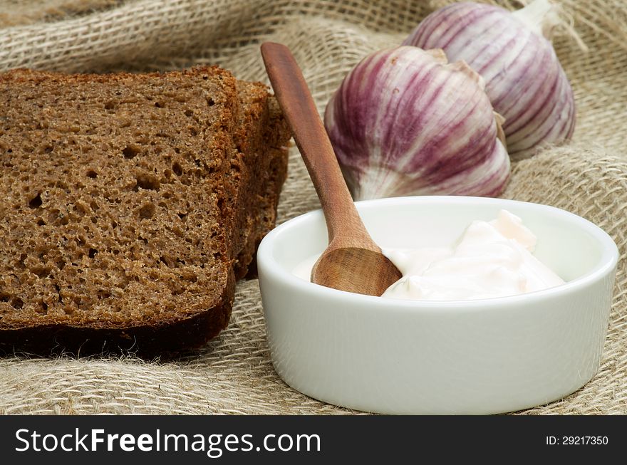Simple Snack with Sour Cream, Garlic and Brown Bread closeup on Sackcloth background