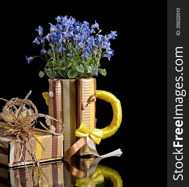 Paper mug and gift box with bellflowers isolated on a black background. Paper mug and gift box with bellflowers isolated on a black background