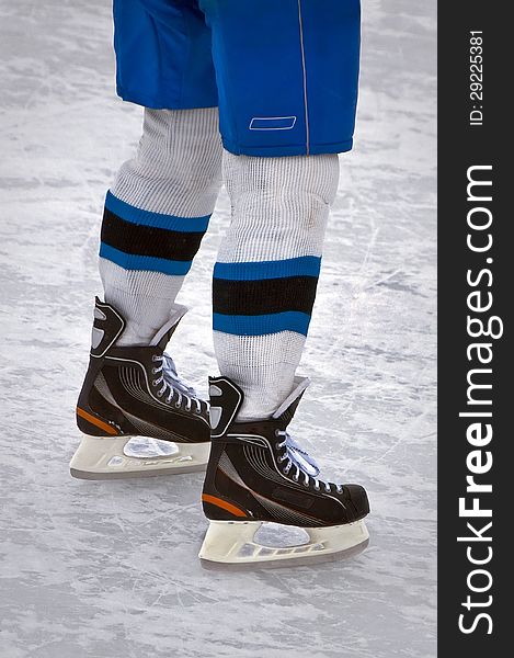 Legs hockey player in uniform standing on skates on ice