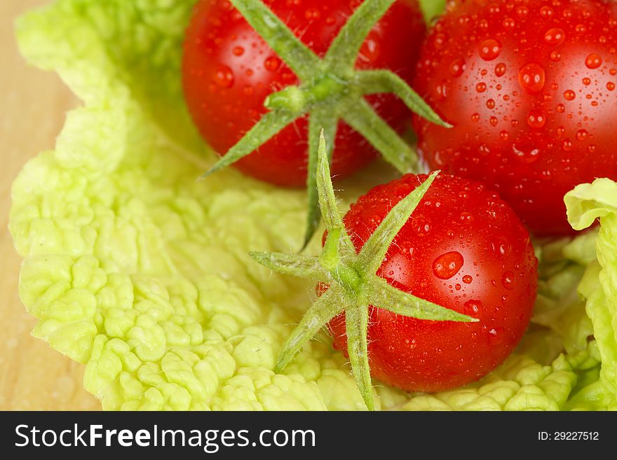 Fresh and wet tomatoes lying on the salad leaves