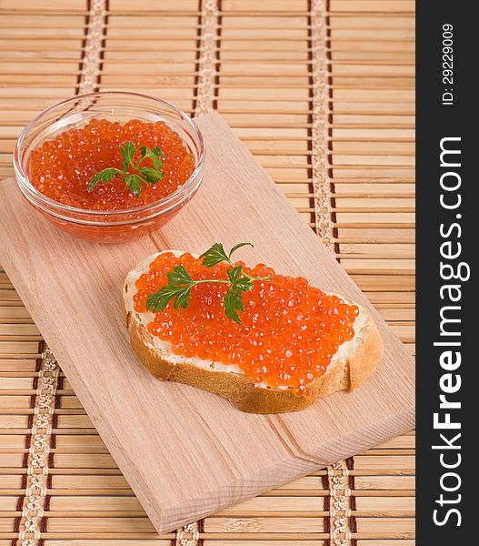 Bread with red caviar on wood